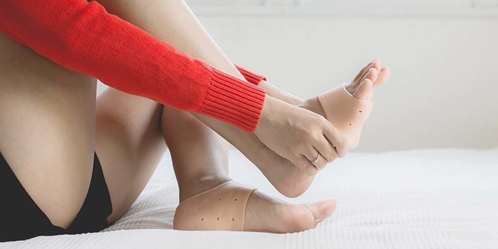 Woman using support silicone for treatment plantar fasciitis on her foot